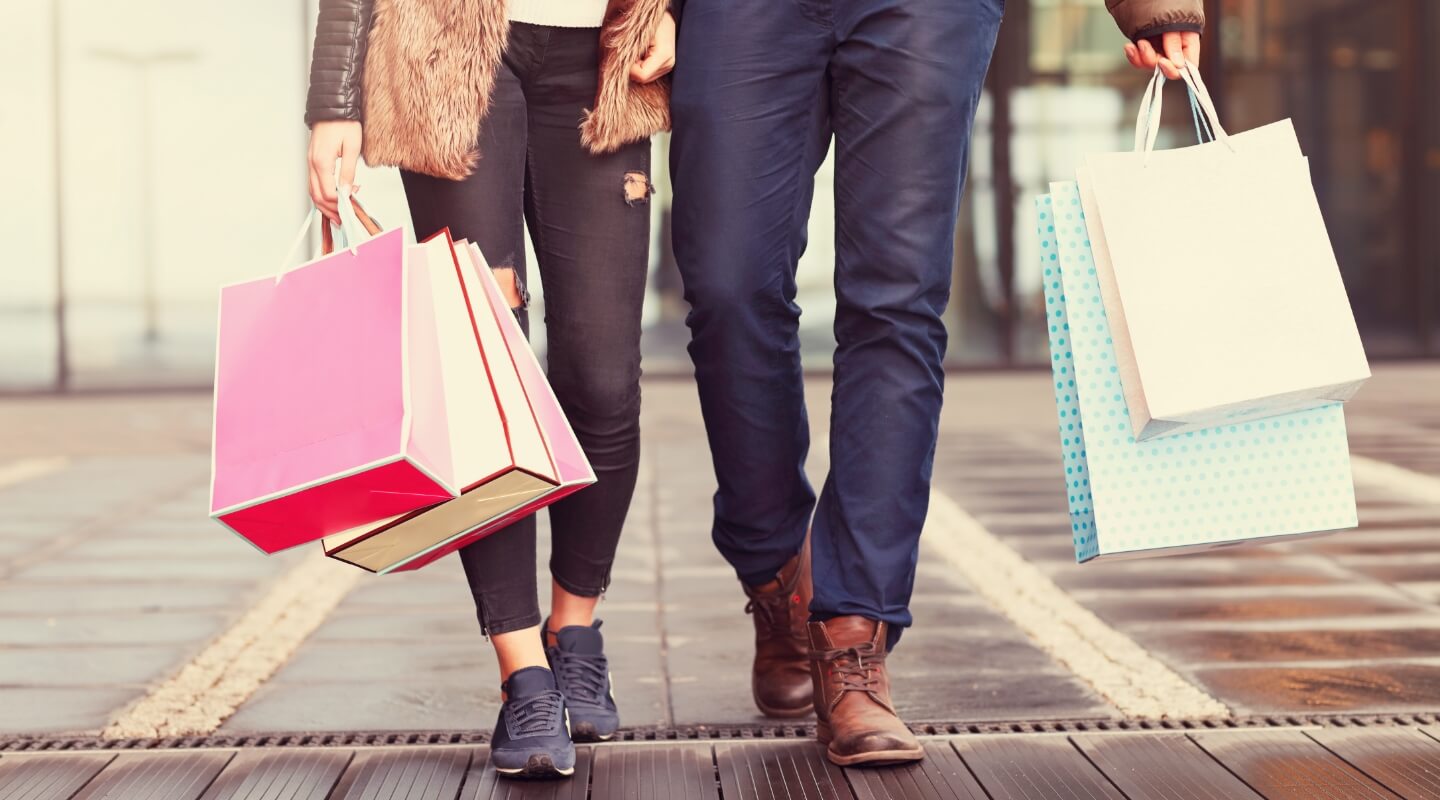 man and a woman walking holding shopping bags