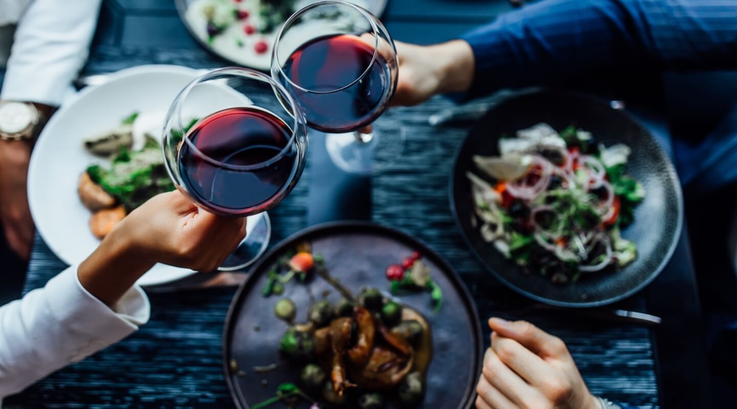 two people cheersing wine glasses over dinner